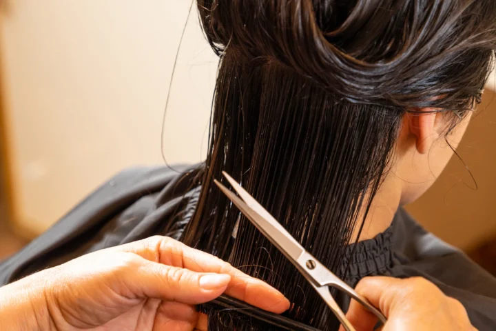 Coiffeuse coupant aux ciseaux les cheveux d'une jeune femme au salon