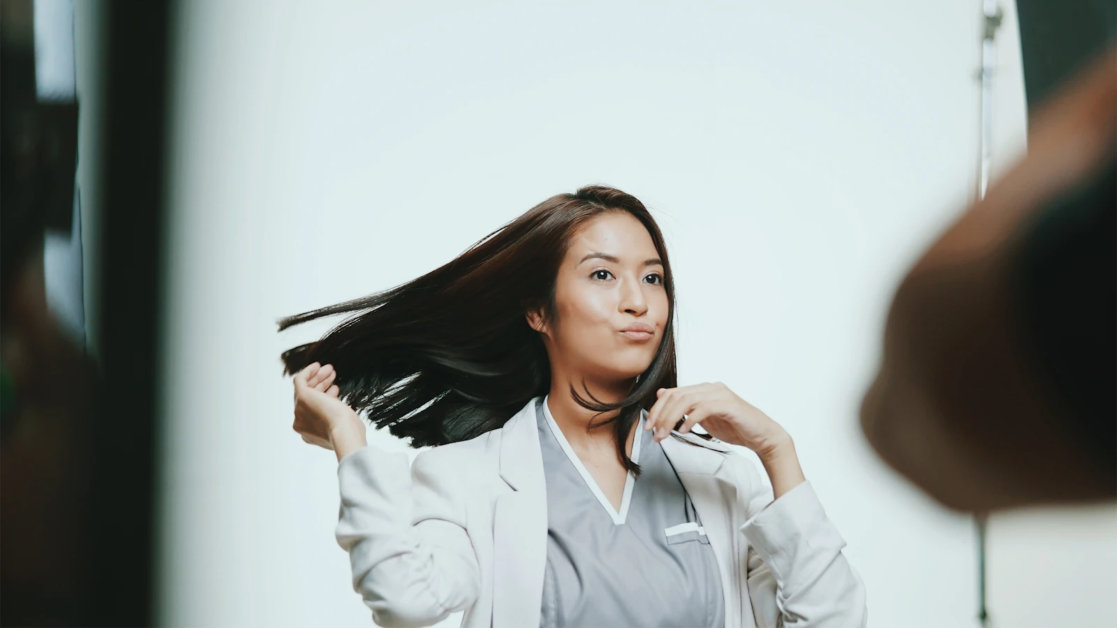 Femme en chemise blanche qui rassemble ses cheveux d'une main