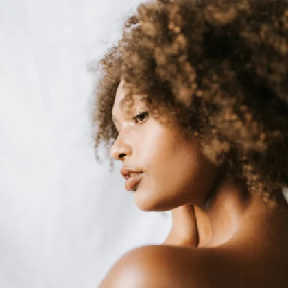 Femme aux cheveux texturés vue de profil, regard tourné vers la gauche